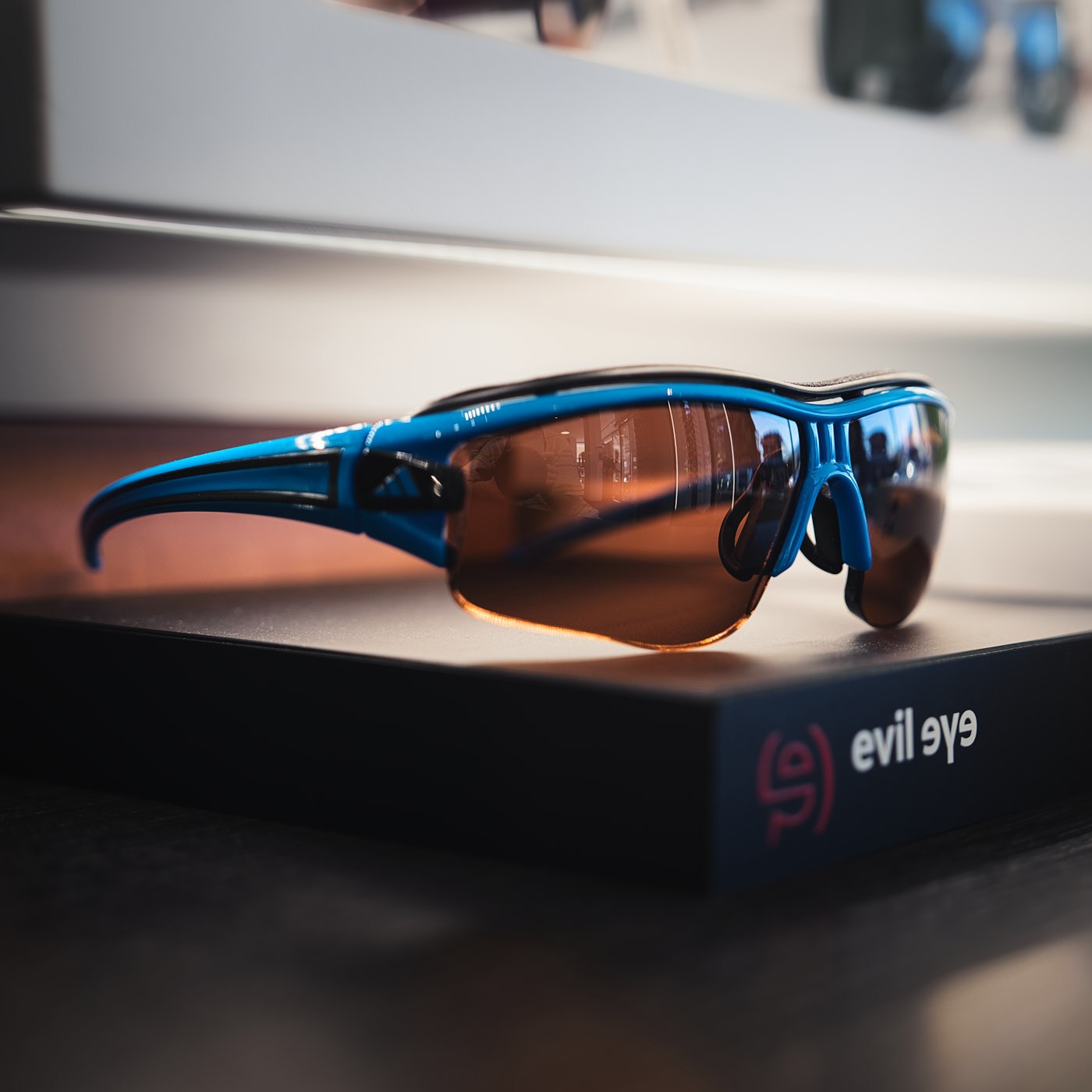 Produktfotografie einer Sportbrille im Optikergeschäft mit selektiver Schärfe, Lichtreflexen und modernem Design.