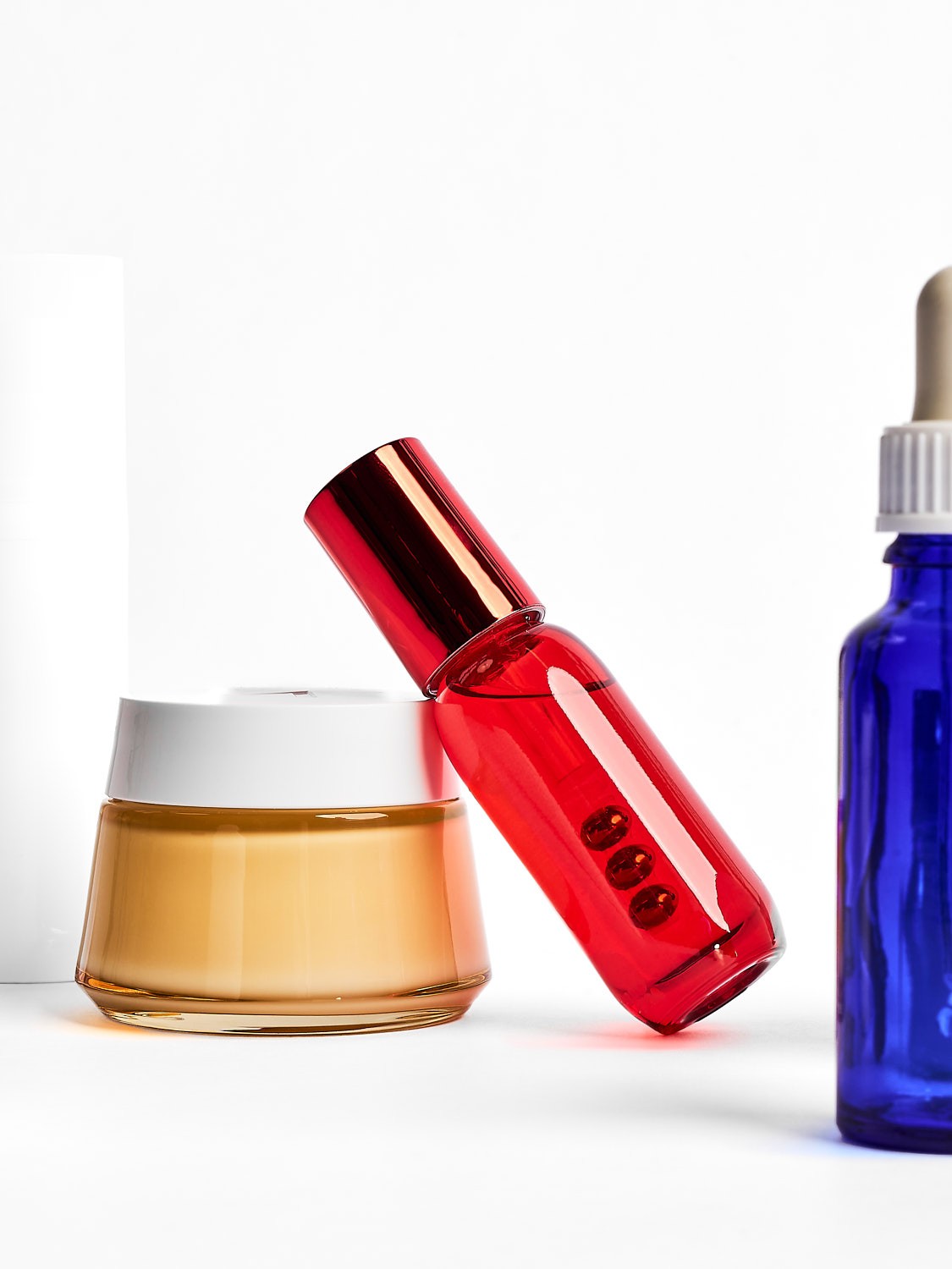 Moderne Produktfotografie von Kosmetikflaschen und Creme, farbige Glasverpackungen mit Dropper, für hochwertige Beauty Markenpräsentation
