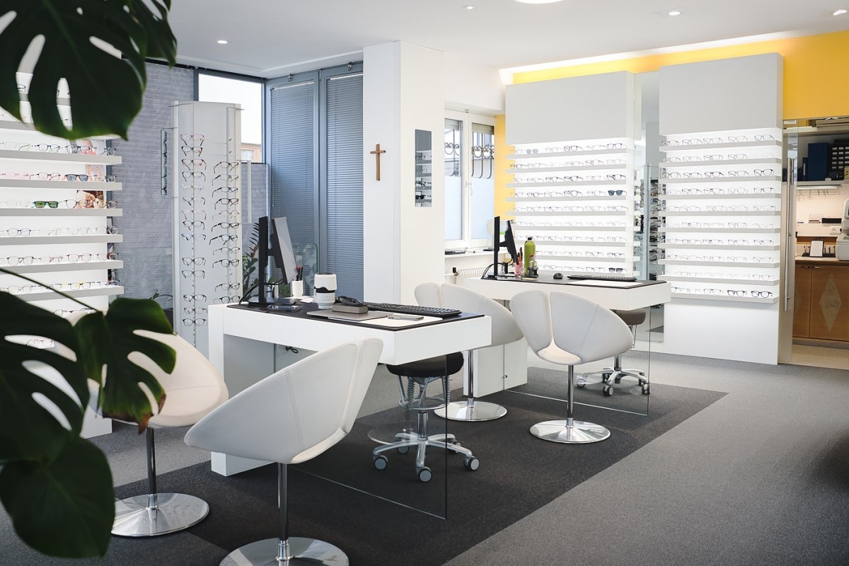 Innenraumfotografie eines modernen Optikergeschäfts mit heller Gestaltung, Brillenpräsentation und klaren Linien.