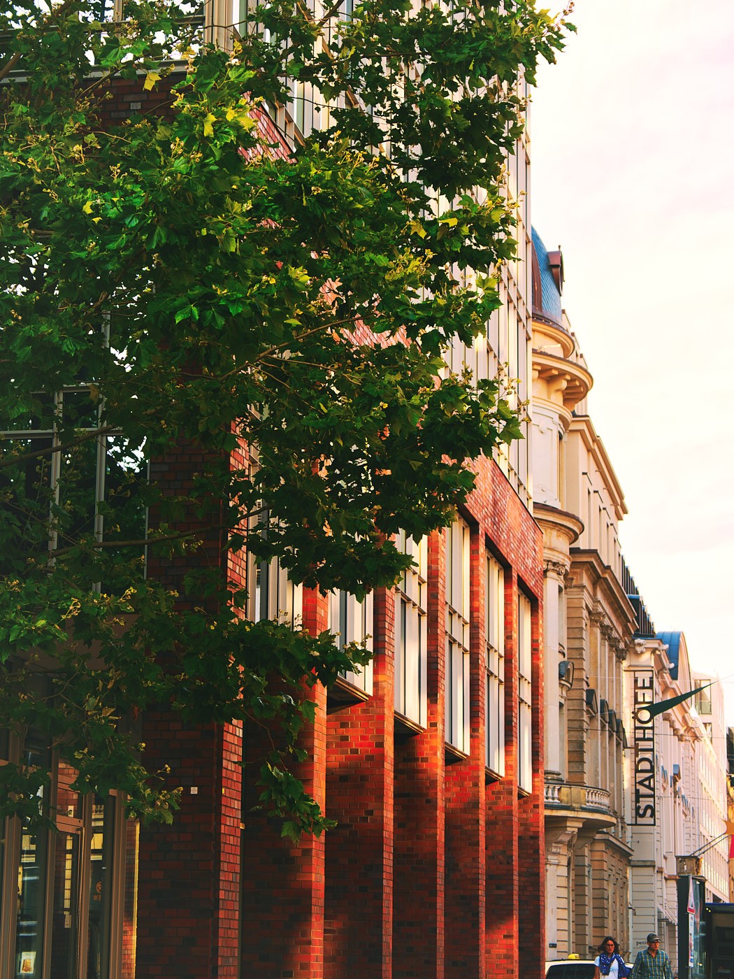 Stadtfotografie moderner Hamburger Architektur mit Backsteinfassade, grünen Bäumen und urbaner Atmosphäre.