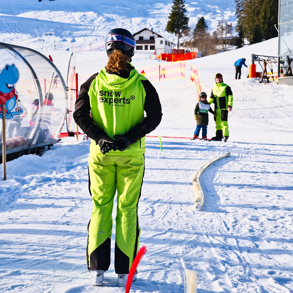 Skischule mit Kindern und Skilehrern im sonnigen Winterresort – authentische Tourismusfotografie im Schnee.