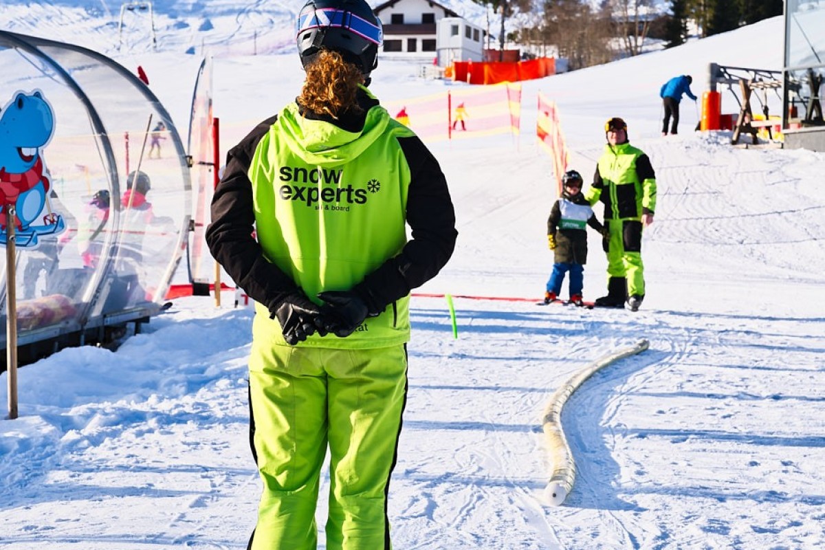 Authentische Imagefotografie eines Skilehrers auf der Anfängerpiste, winterliches Outdoor Ambiente mit Fokus auf Betreuung und Erlebnis
