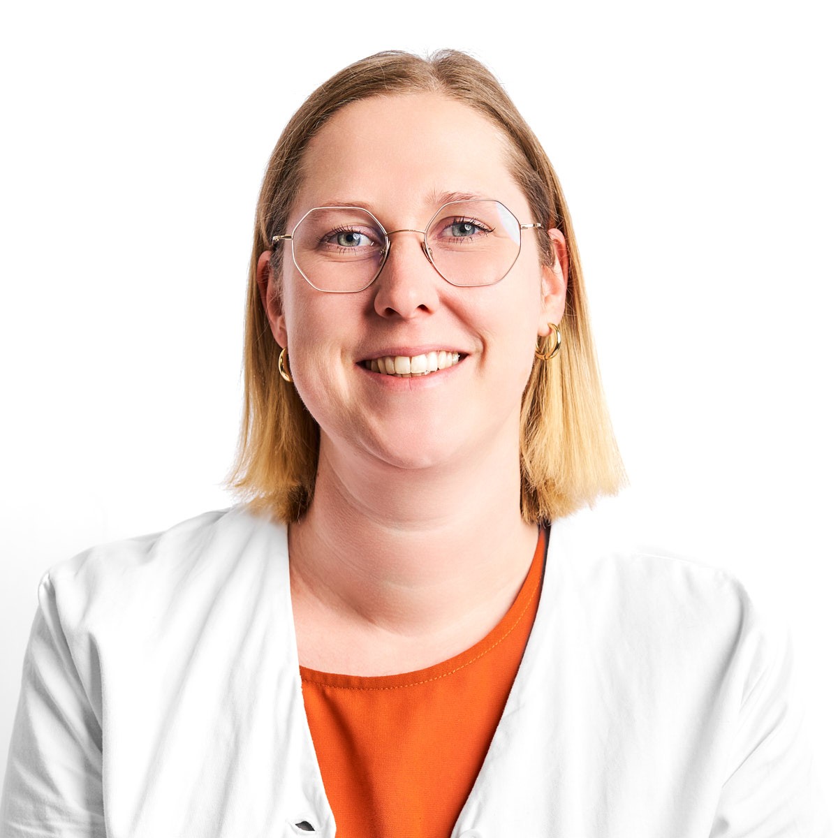 Portrait einer Apothekerin mit Brille und weißem Kittel – authentisches Mitarbeiterfoto vor hellem Hintergrund.