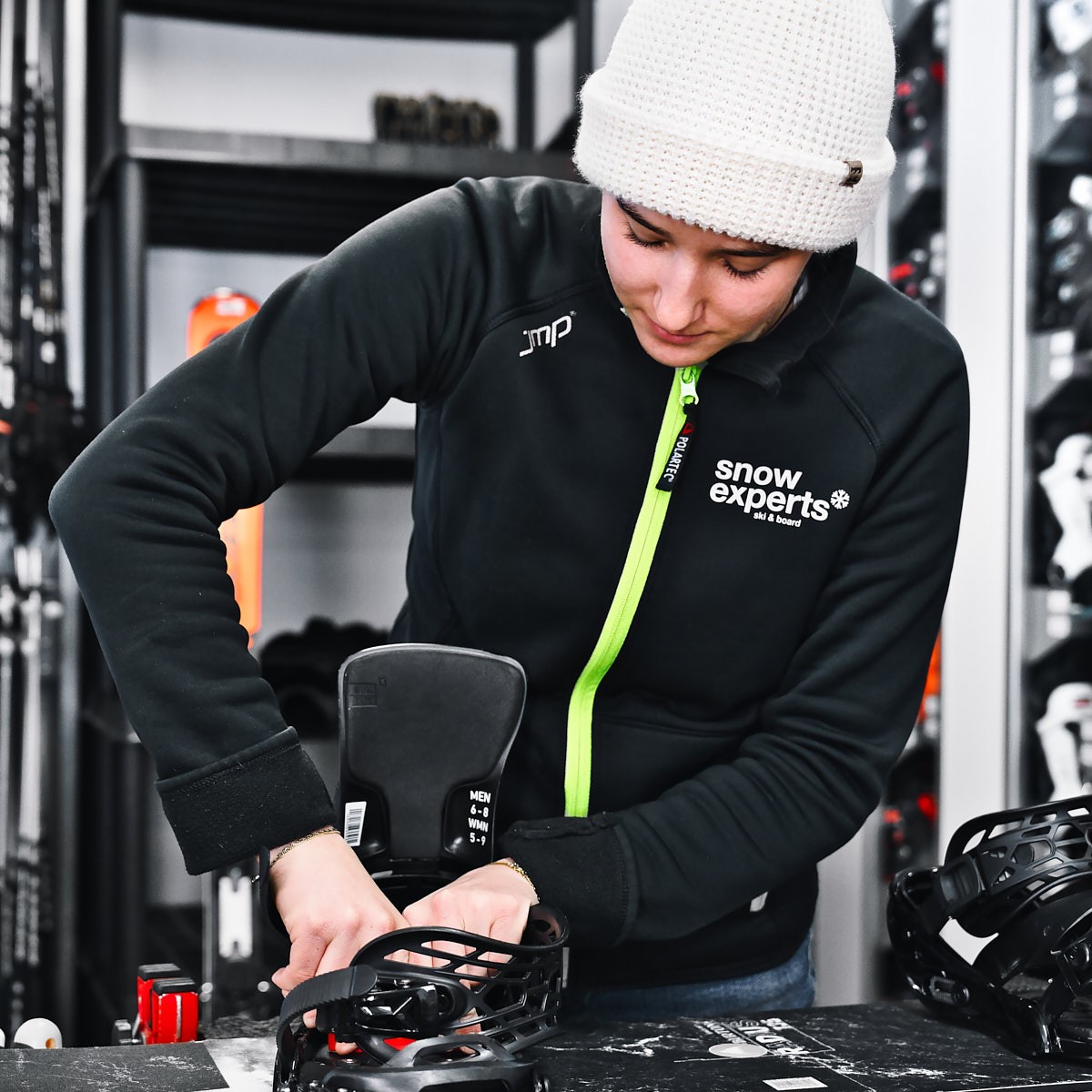 Mitarbeiterin beim Einstellen eines Snowboards im Verleih – authentische Teamaufnahme im Wintersport-Alltag.