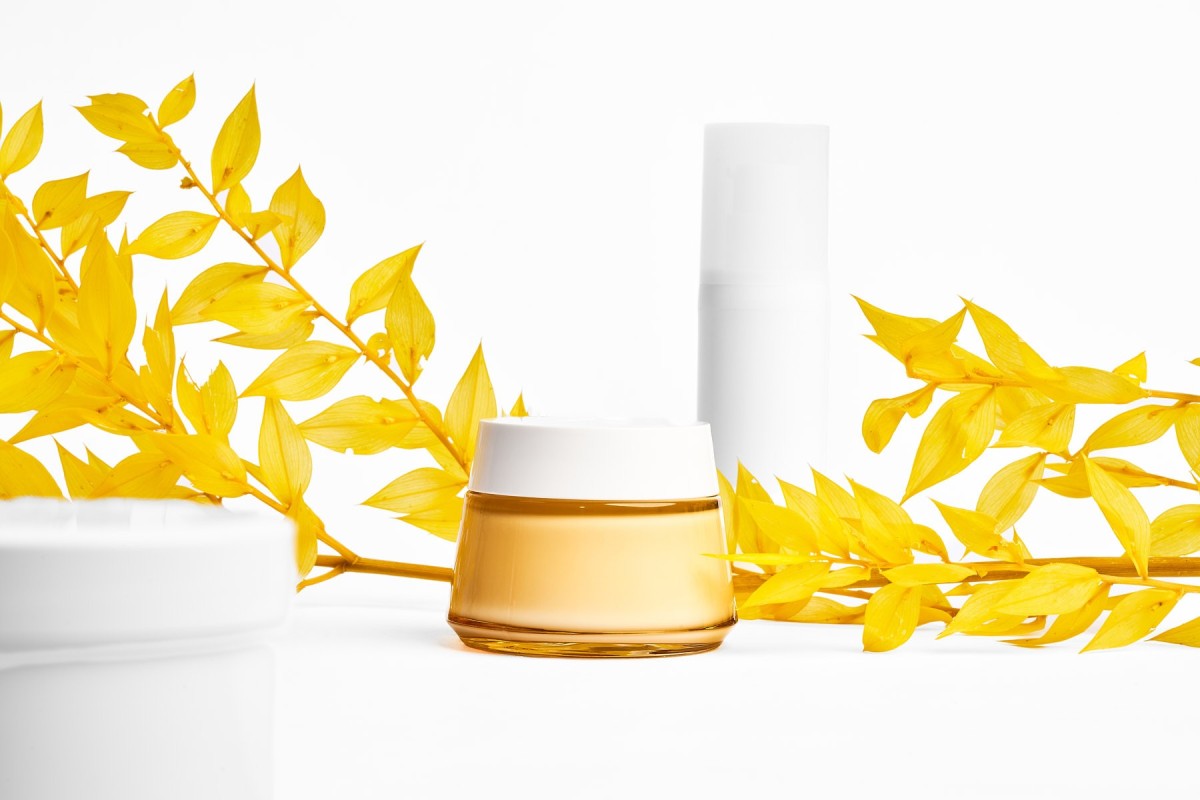 Minimalistische Produktfotografie von Kosmetik Creme und Flakon mit gelben Blättern, cleanes Studio Setup für Beauty Branding