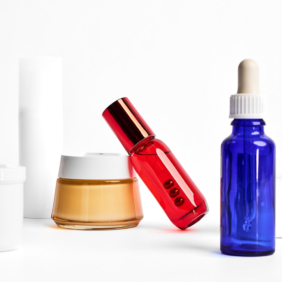 Moderne Produktfotografie von Kosmetikflaschen und Creme, farbige Glasverpackungen mit Dropper, für hochwertige Beauty Markenpräsentation