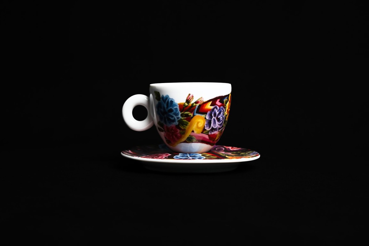 Produktfotografie einer bunten Espressotasse mit Untertasse auf schwarzem Hintergrund, dramatisches Licht für stilvolle Präsentation