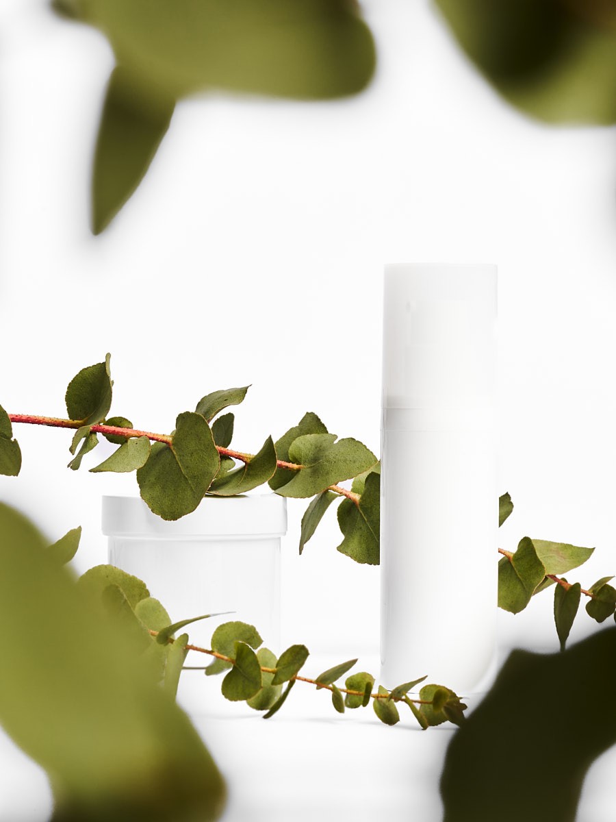 Produktfotografie eines Kosmetik Mockups mit weißem Tiegel und Flakon, umrahmt von Eukalyptus, Studio Setup für Branding und Werbung
