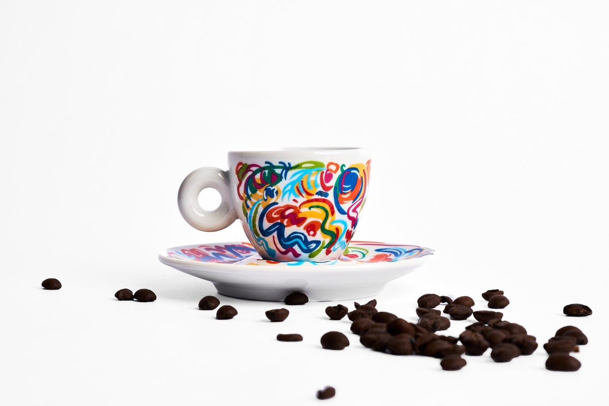 Produktfotografie einer bunten Espressotasse mit Kaffeebohnen, cleanes Studio Setup auf weißem Hintergrund für Markenpräsentation