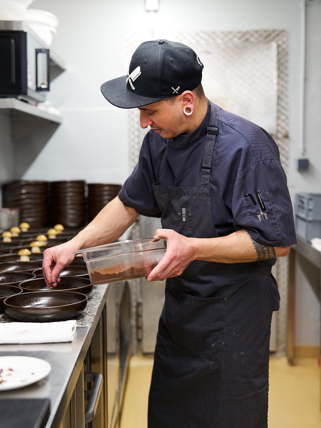 Businessfotografie eines Patissiers bei der Dessertzubereitung in der Backstube, authentisch und detailreich.